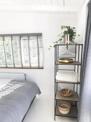 a bedroom with a bed and a shelf next to a window at Little Beach House in Zandvoort