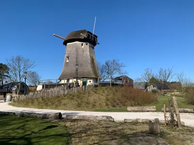 a building with a windmill on top of a hill at De Molen van Egmond by Droomvilla in Egmond aan den Hoef