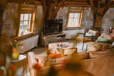 a living room with a couch and a tv at De Molen van Egmond by Droomvilla in Egmond aan den Hoef
