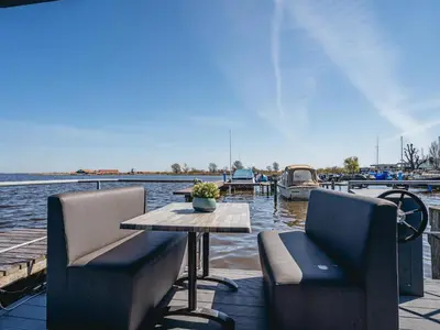 a table and two chairs on a dock with a boat at Luxury Houseboat Getaway in Uitgeest
