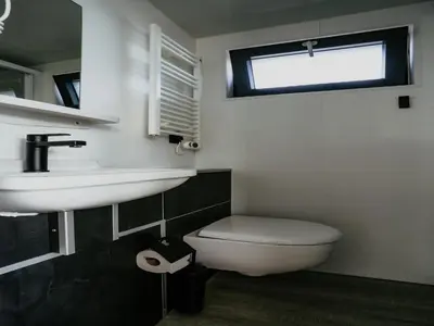 a bathroom with a sink and a toilet and a window at Luxury Houseboat Getaway in Uitgeest