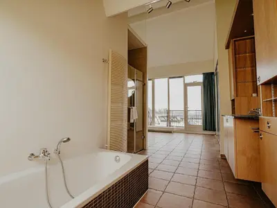 a large bathroom with a tub and a large window at Penthouse with Lake Views in Uitgeest