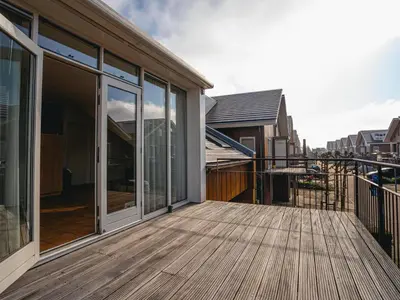 a deck with sliding glass doors on a house at Penthouse with Lake Views in Uitgeest