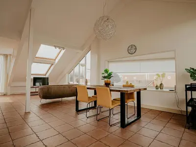 a living room with a table and chairs and a couch at Penthouse with Lake Views in Uitgeest