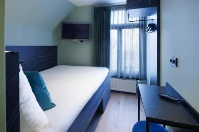 a small hotel room with a bed and a television at Ciao Papa Hotel Amsterdam Central Station in Amsterdam