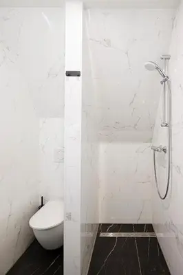 a white bathroom with a shower and a toilet at Ciao Papa Hotel Amsterdam Central Station in Amsterdam