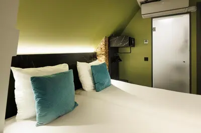 a bedroom with a large bed with two blue pillows at Ciao Papa Hotel Amsterdam Central Station in Amsterdam