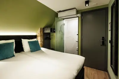 a bedroom with a large white bed with blue pillows at Ciao Papa Hotel Amsterdam Central Station in Amsterdam