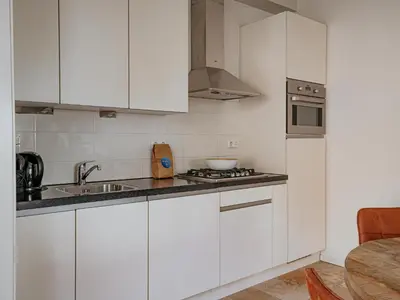 a white kitchen with a sink and a stove at De Platvis in Egmond aan Zee