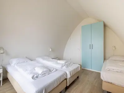 a bedroom with two beds and a blue cabinet at De Platvis in Egmond aan Zee
