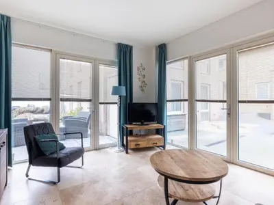 a living room with a tv and a chair and a table at De Platvis in Egmond aan Zee