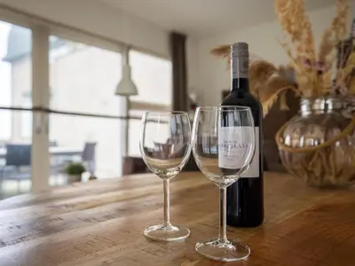a bottle of wine and two wine glasses on a wooden table at Zeebaars in Egmond aan Zee