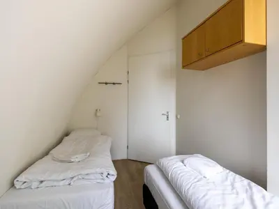 two beds in a room with white walls at Zeebaars in Egmond aan Zee