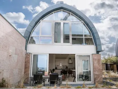 a house with an arched window and a dining room at Zeebaars in Egmond aan Zee