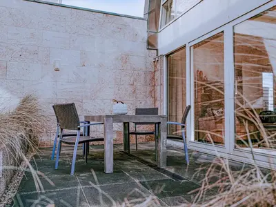 a wooden table and chairs on a patio at Zeebaars in Egmond aan Zee