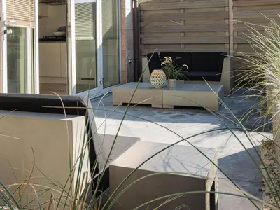 a patio with a bench and potted plants on it at Zeebaars in Egmond aan Zee