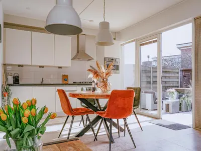 a kitchen with a wooden table and orange chairs at Zeebaars in Egmond aan Zee
