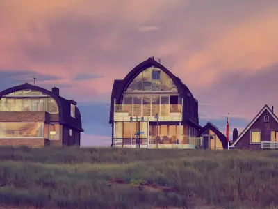 a large glass house on top of a field at De Kreeft in Egmond aan Zee