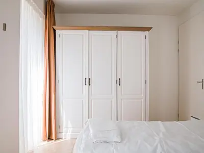 a bedroom with a white bed and a window at De Kreeft in Egmond aan Zee