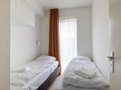 two beds in a room with a window at De Kreeft in Egmond aan Zee