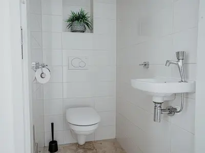 a white bathroom with a toilet and a sink at De Kreeft in Egmond aan Zee