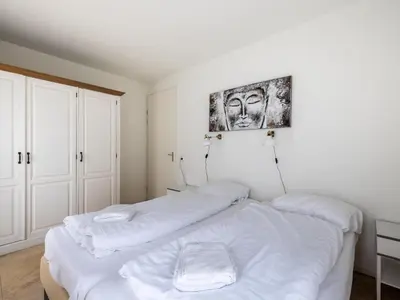 a bedroom with two beds and a picture on the wall at De Kreeft in Egmond aan Zee