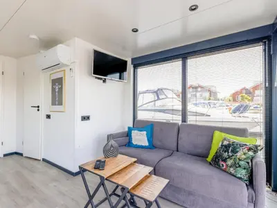 a living room with a couch and a table at Tiny houseboat Parel I - airco in Uitgeest