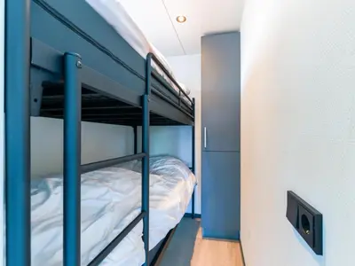 a bunk bed in a room with blue walls and a bunk bedutenewayangering at Tiny houseboat Parel I - airco in Uitgeest