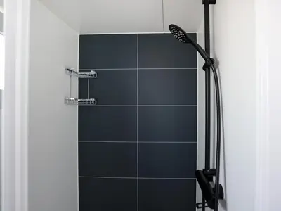 a bathroom with a shower with blue tiles at Tiny houseboat Parel I - airco in Uitgeest