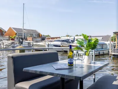 a table with two glasses and a bottle of wine at Tiny houseboat Parel I - airco in Uitgeest