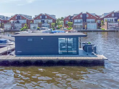 a small house on a dock on a body of water at Tiny houseboat Parel I - airco in Uitgeest