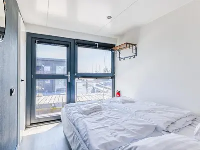 two beds in a room with a large window at Tiny houseboat Parel I - airco in Uitgeest