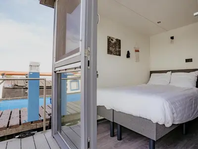 a bedroom with a bed and a balcony at Tiny houseboat Uitgeest I in Uitgeest