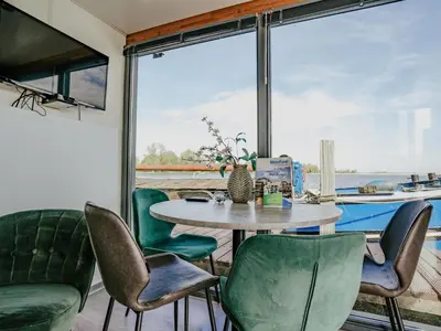 a dining room with a table and green chairs at Tiny houseboat Uitgeest I in Uitgeest