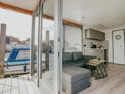 a living room with a couch and a table at Tiny houseboat Uitgeest I in Uitgeest