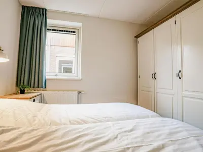 a bedroom with a white bed and a window at Appartement Assum I in Uitgeest