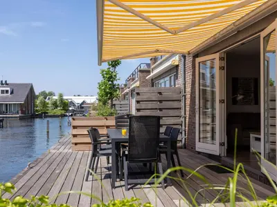 a wooden deck with a table and chairs on it at Appartement Assum I in Uitgeest