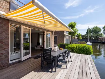 a patio with a table and chairs on a wooden deck at Appartement Assum I in Uitgeest