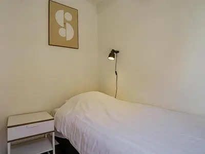 a bedroom with a white bed and a lamp at Het Kraaijennest Miva in Uitgeest