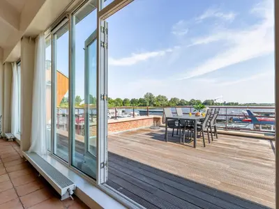 a balcony with a table and chairs looking out over the water at Penthouse in Uitgeest