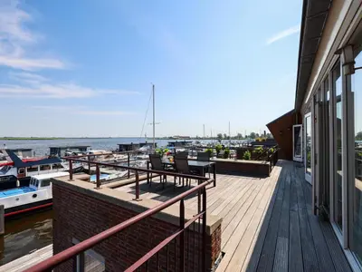 a wooden deck with tables and chairs on a house at Penthouse in Uitgeest