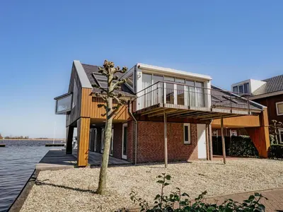 a house on the water with a tree at Penthouse in Uitgeest