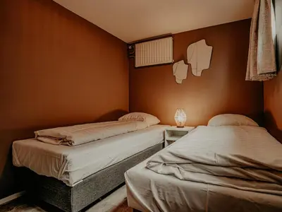 two twin beds in a room with a wall at Woonark De Woude in Uitgeest