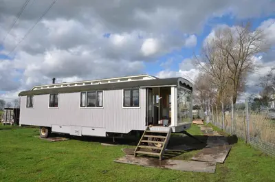a white trailer parked in a field with a ladder at Gypsy Waggon - A villa on wheels in Amsterdam