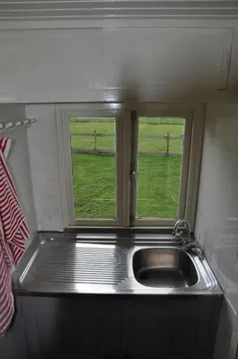 a kitchen with a sink and a window with a field at Gypsy Waggon - A villa on wheels in Amsterdam