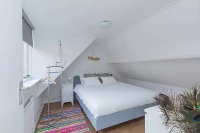 a small bedroom with a bed in a attic at Have a nice stay! - Salty Beachhouse in Noordwijk aan Zee