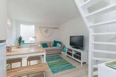 a living room with a couch and a television at Have a nice stay! - Salty Beachhouse in Noordwijk aan Zee