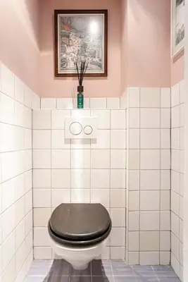 a toilet with a black seat in a white tiled bathroom at Studio Evership just minutes from the beach and center in Zandvoort