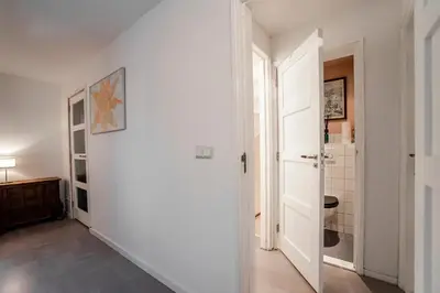 a hallway with a white wall and an open door at Studio Evership just minutes from the beach and center in Zandvoort