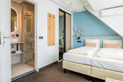 a bedroom with a bed and a bathroom at Huis 8 Studio's in Katwijk aan Zee
